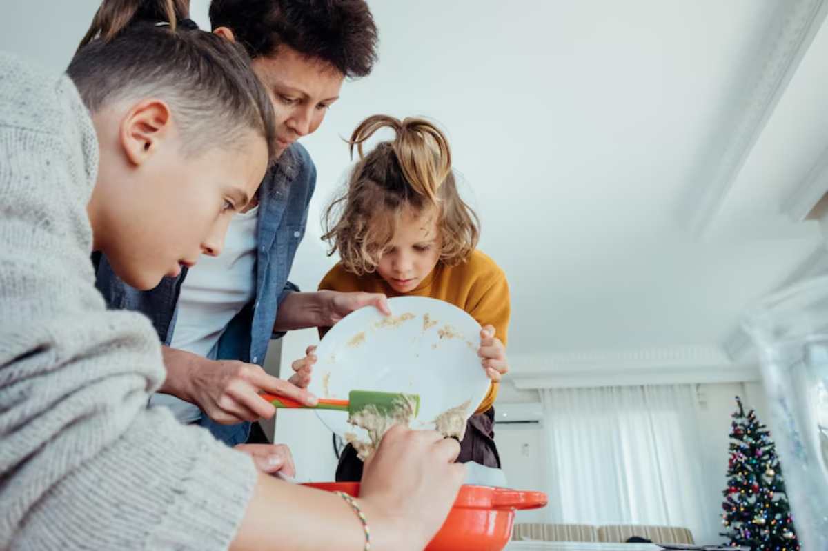 A group of children gather around a mixing bowl, sharing a moment while baking in a brightly lit kitchen.
