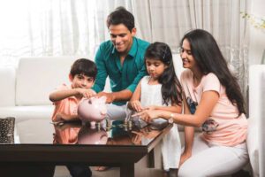 A family sitting around a table, joyfully counting coins and interacting with a pink piggy bank, in a bright, cozy living room.