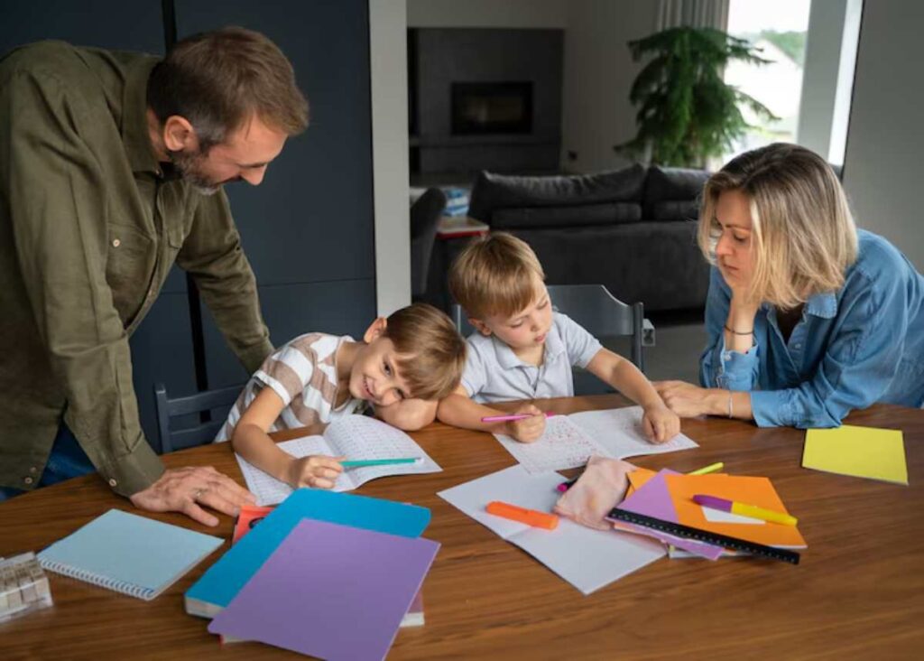 A family gathers around a table filled with colorful papers and stationery, engaged in a creative activity.