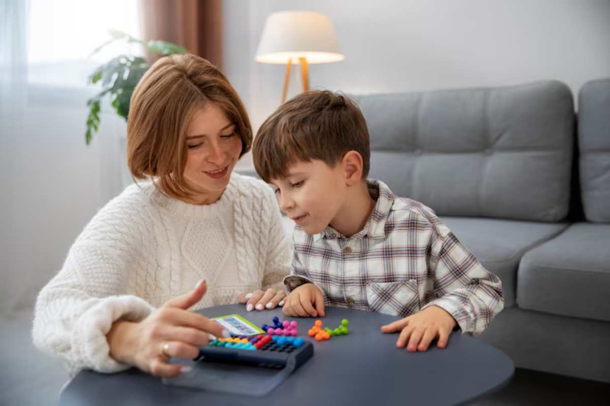 A child and adult interact at a table, engaging with colorful counting manipulatives and a calculator in a cozy living room setting.