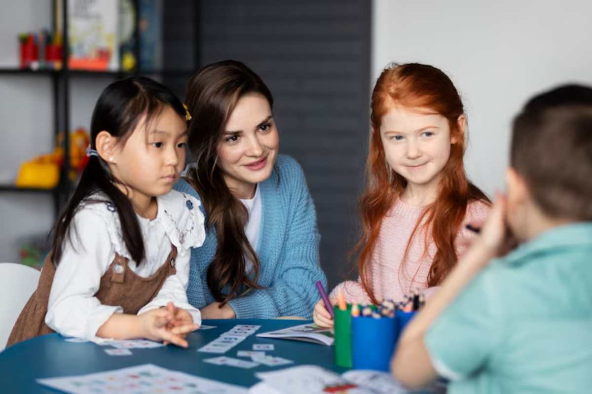 A group of children engaged in creative activities around a table with art supplies and colorful drawings in a bright, casual setting.