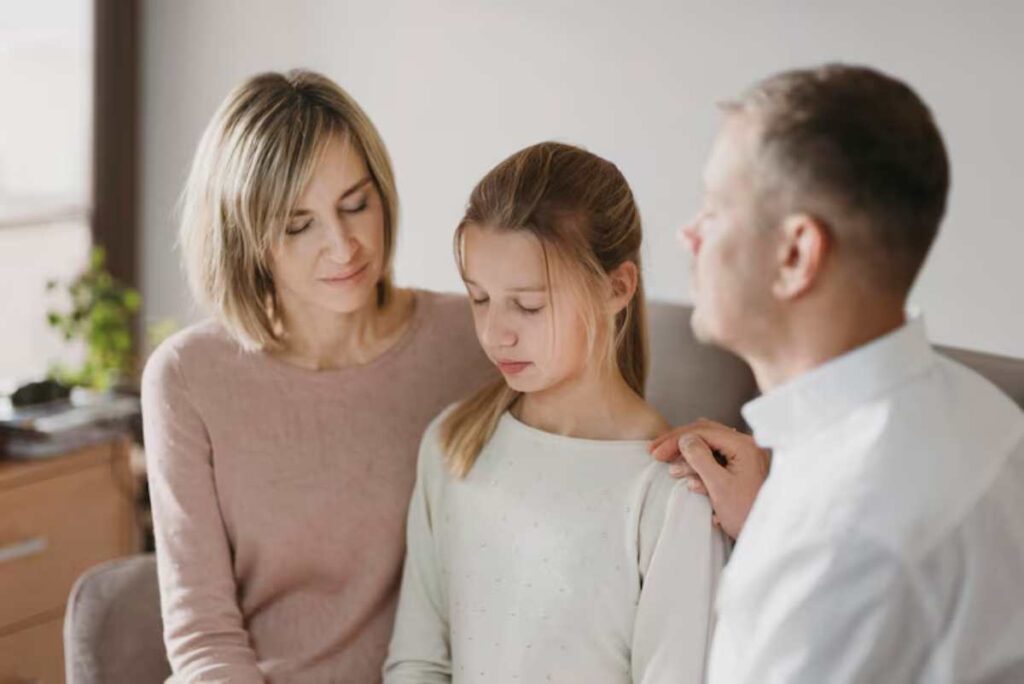 A family sitting together on a sofa in a modern living room, engaged in a supportive conversation.